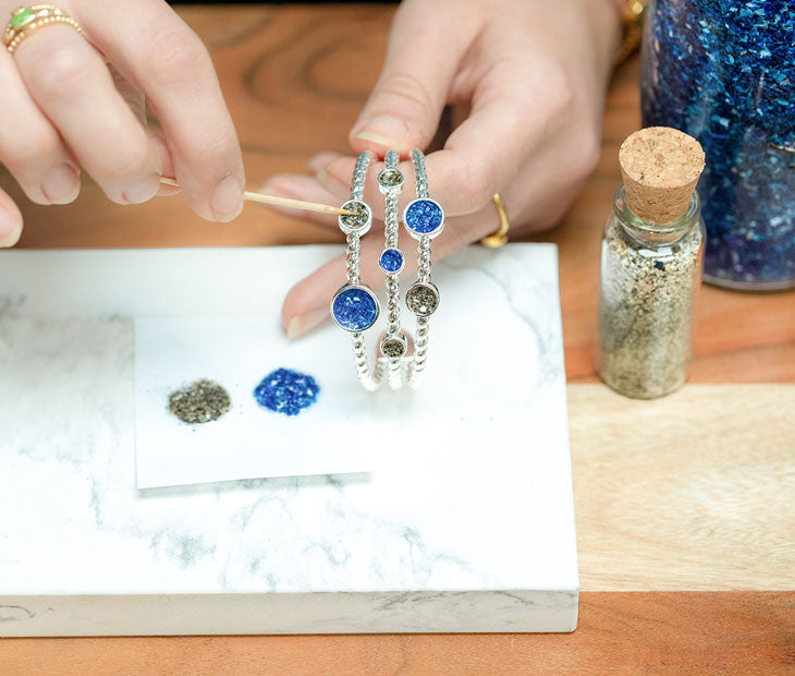 A person placing sand particles in the Dune Bali Bracelet