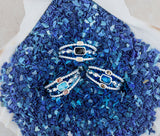 A set of 3 Dune Bali Rings on top of a mound of blue plastic flakes that are used to make the rings